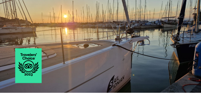 Golden sunset over a marina with boats lined up, reflecting on calm water, and a "Travelers' Choice Award 2023" badge in the foreground on the left.