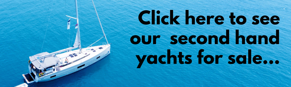 Aerial view of a white yacht sailing in clear blue water with text overlay saying "click here to see our yachts for sale at Yacht Brokerage...